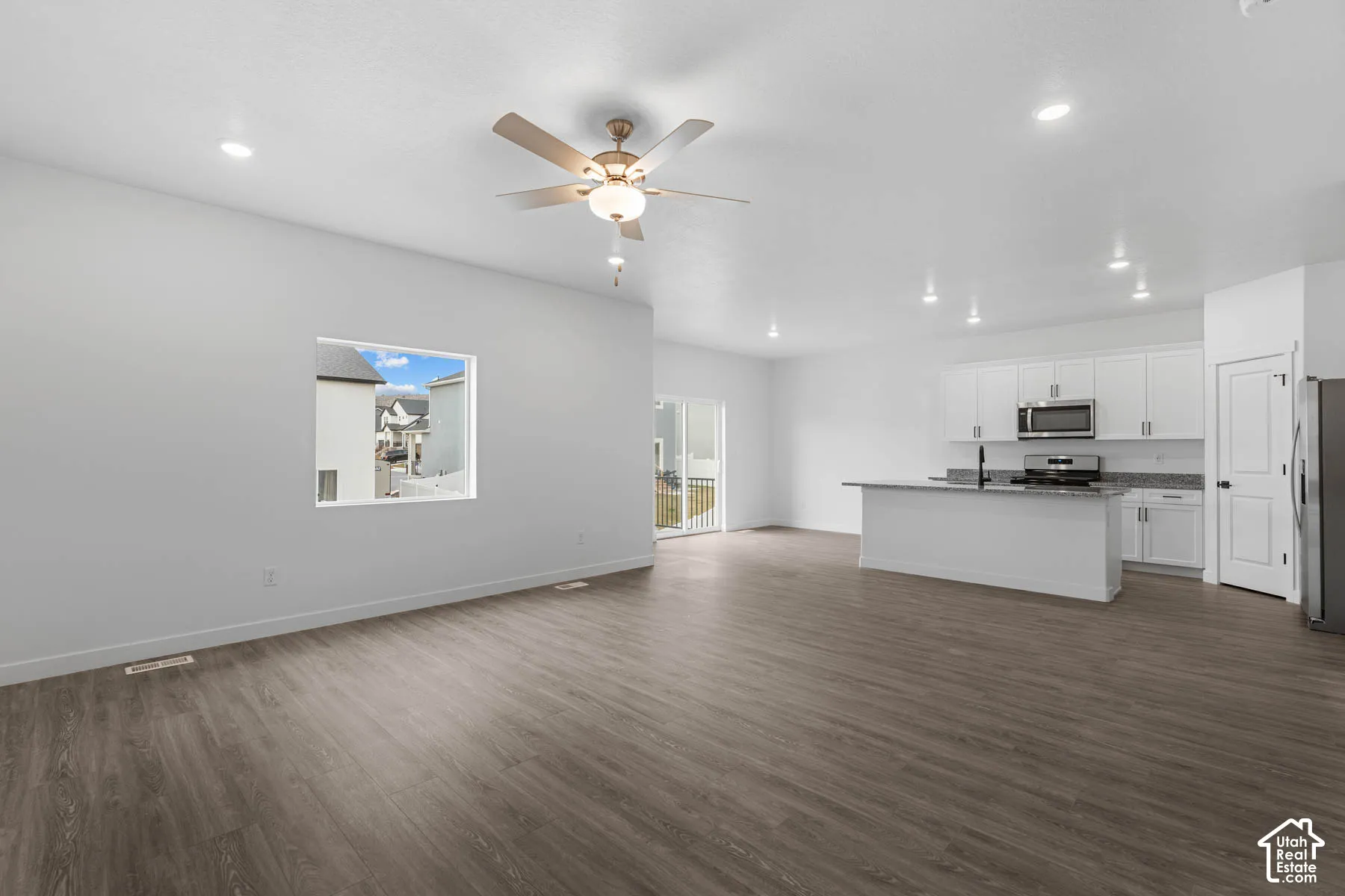Unfurnished living room with dark wood finished floors, a ceiling fan, and recessed lighting