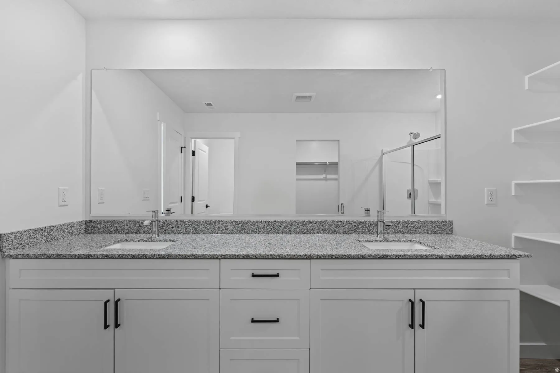 Bathroom featuring a shower stall, double vanity, and a spacious closet