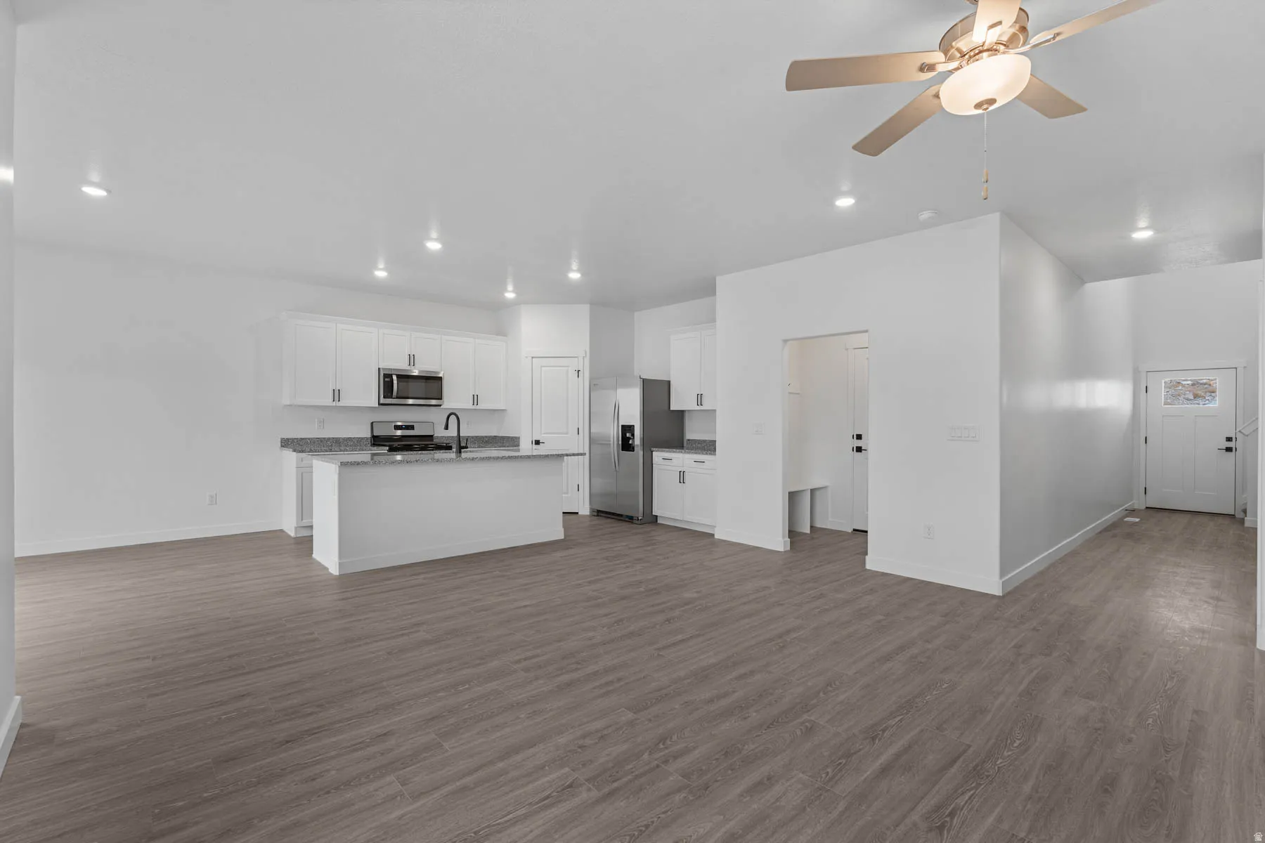 Kitchen with a ceiling fan, open floor plan, white cabinets, stainless steel appliances, and recessed lighting