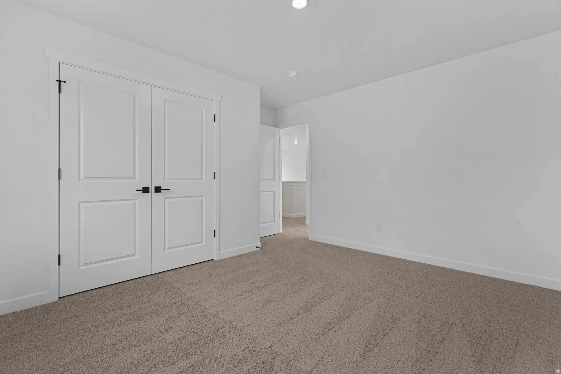 Unfurnished bedroom with light carpet and a closet