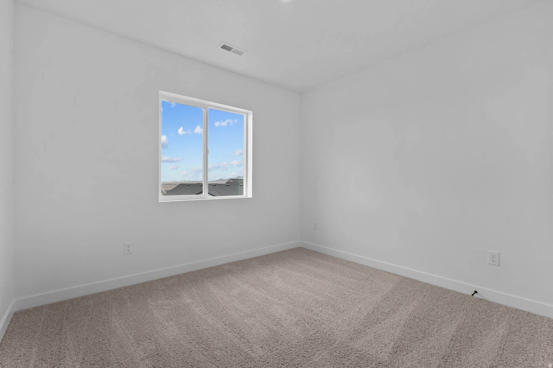 Unfurnished room featuring light carpet and baseboards