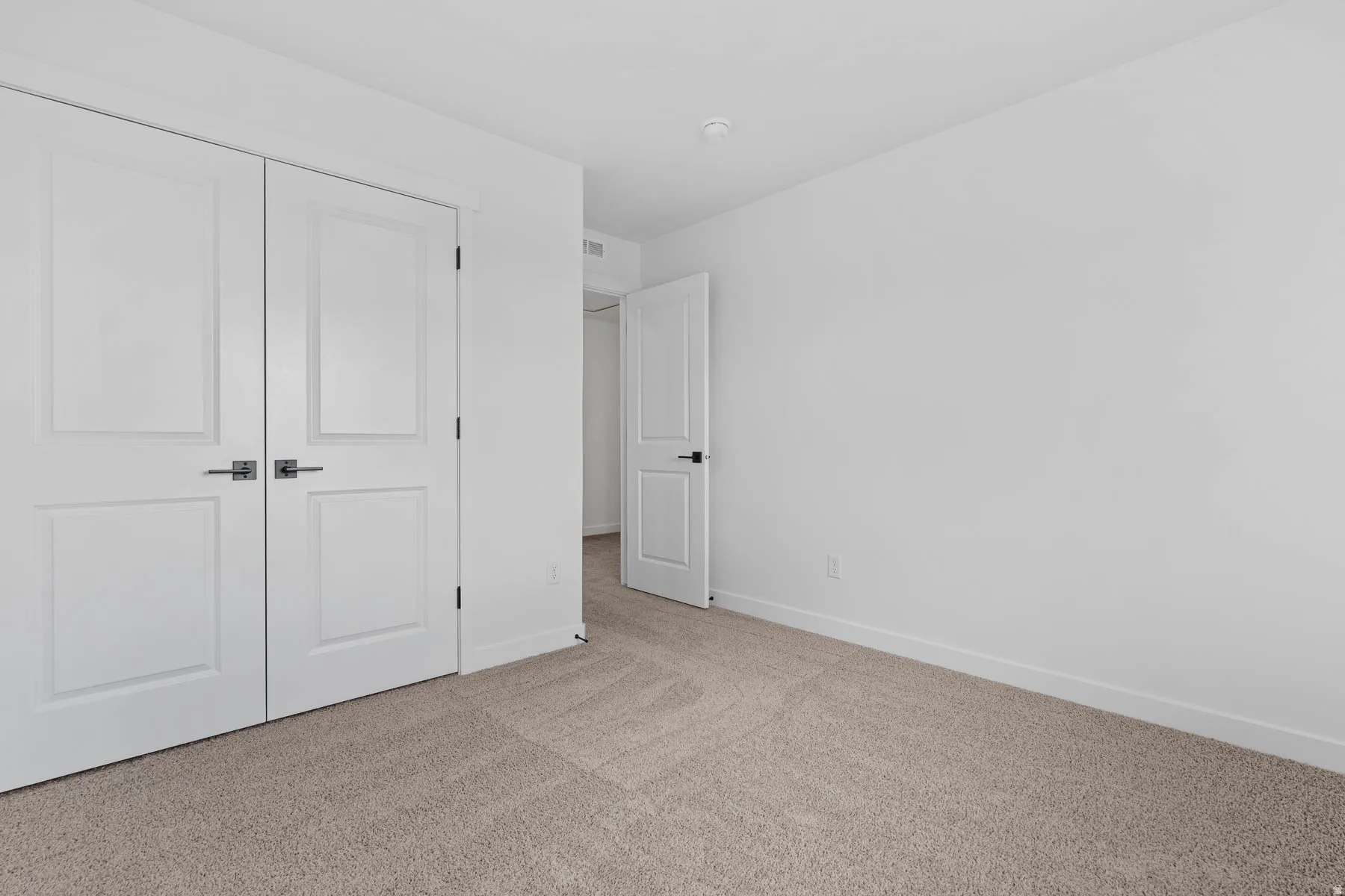 Unfurnished bedroom with light colored carpet and a closet