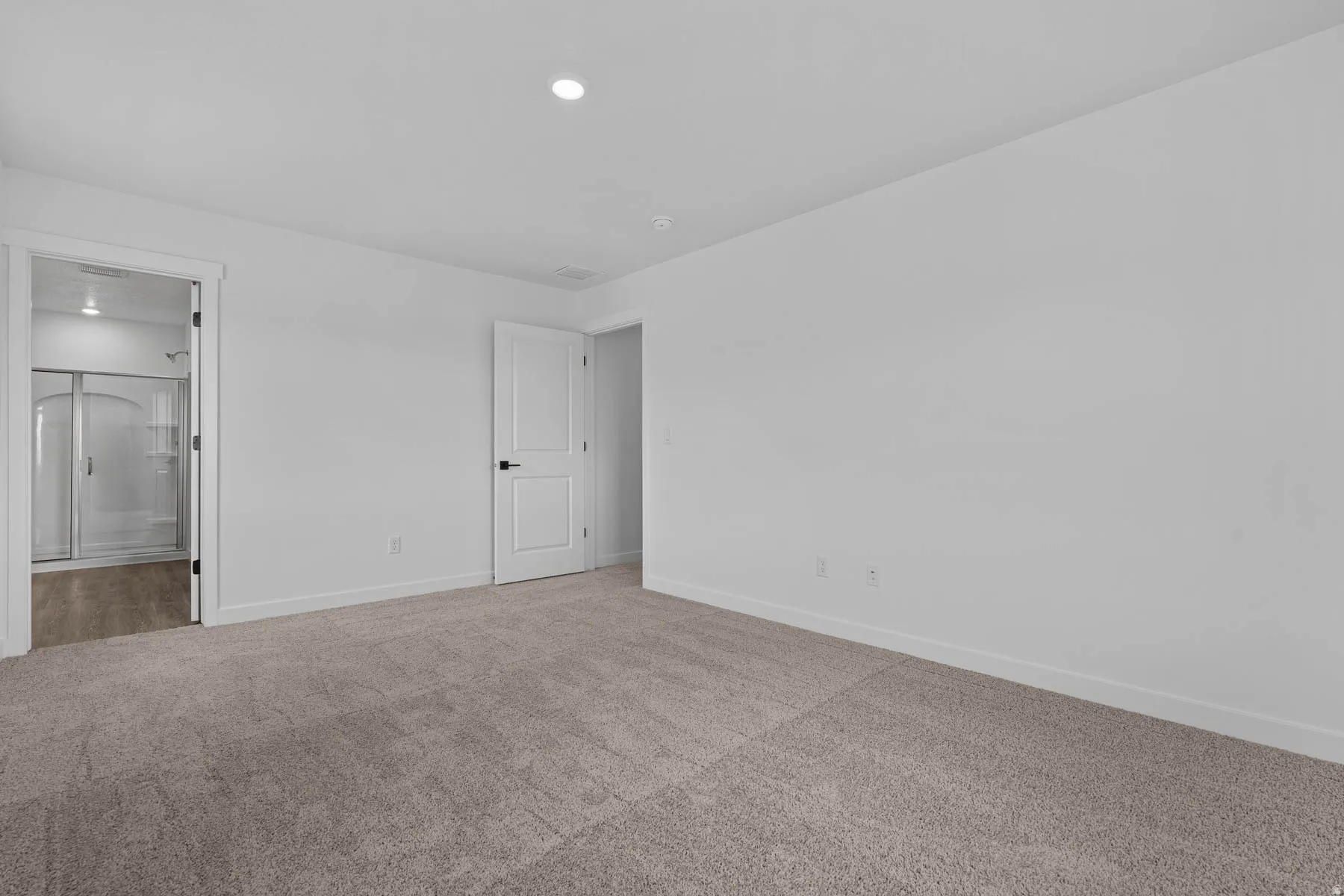 Unfurnished bedroom featuring light carpet and ensuite bathroom