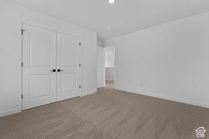 Unfurnished bedroom with light carpet and a closet