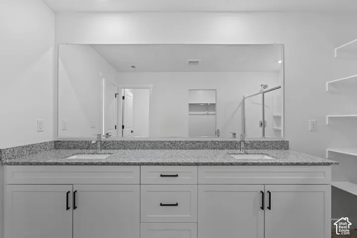 Bathroom featuring a shower stall, double vanity, and a spacious closet