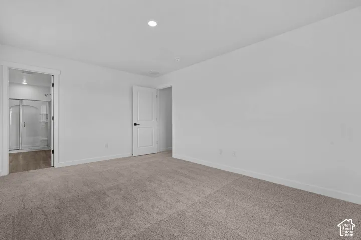 Unfurnished bedroom featuring light carpet and ensuite bathroom