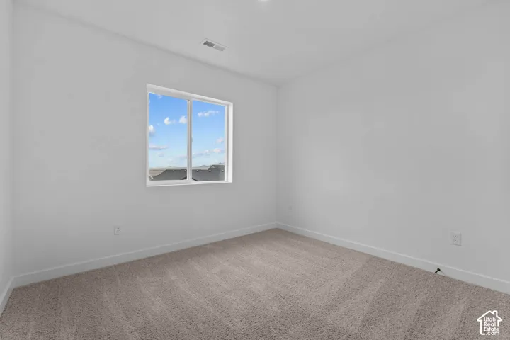 Unfurnished room featuring light carpet and baseboards