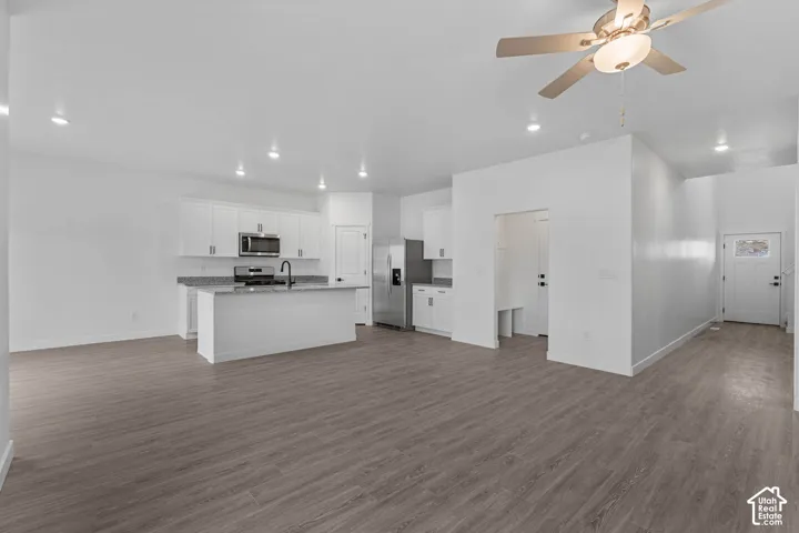 Kitchen with a ceiling fan, open floor plan, white cabinets, stainless steel appliances, and recessed lighting