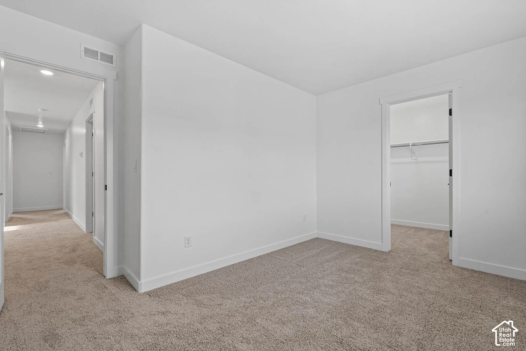 Unfurnished bedroom featuring a spacious closet, light colored carpet, and recessed lighting