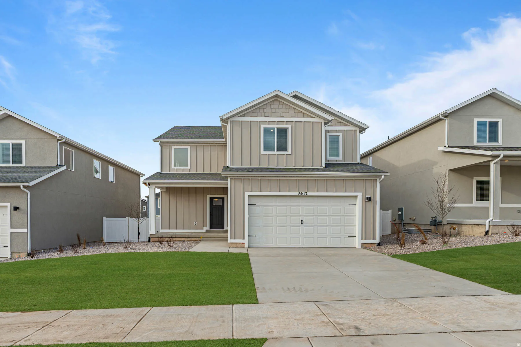 View of front of house with board and batten siding, covered porch, a garage, and driveway