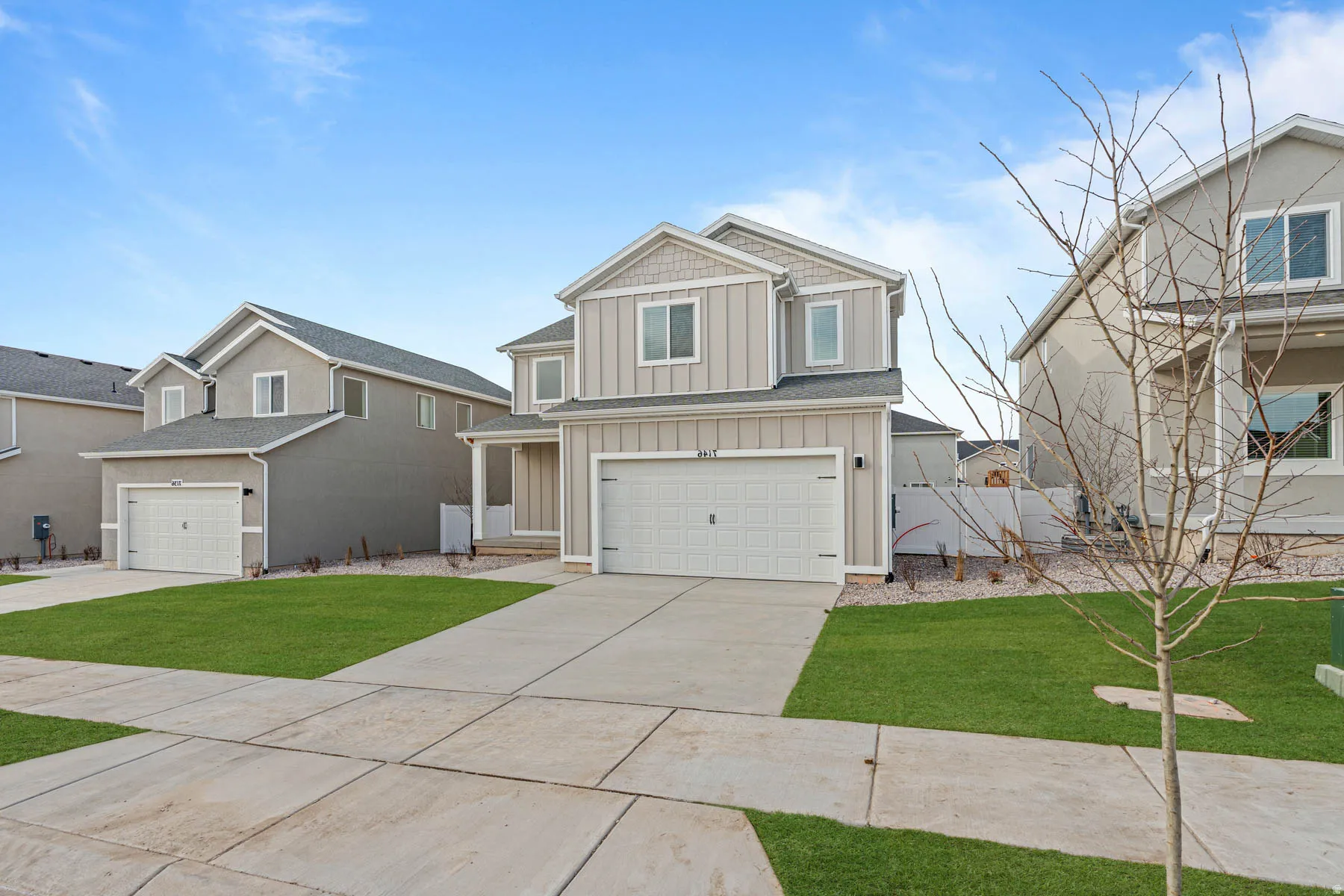 View of front of property featuring board and batten siding, a front lawn, driveway, and an attached garage