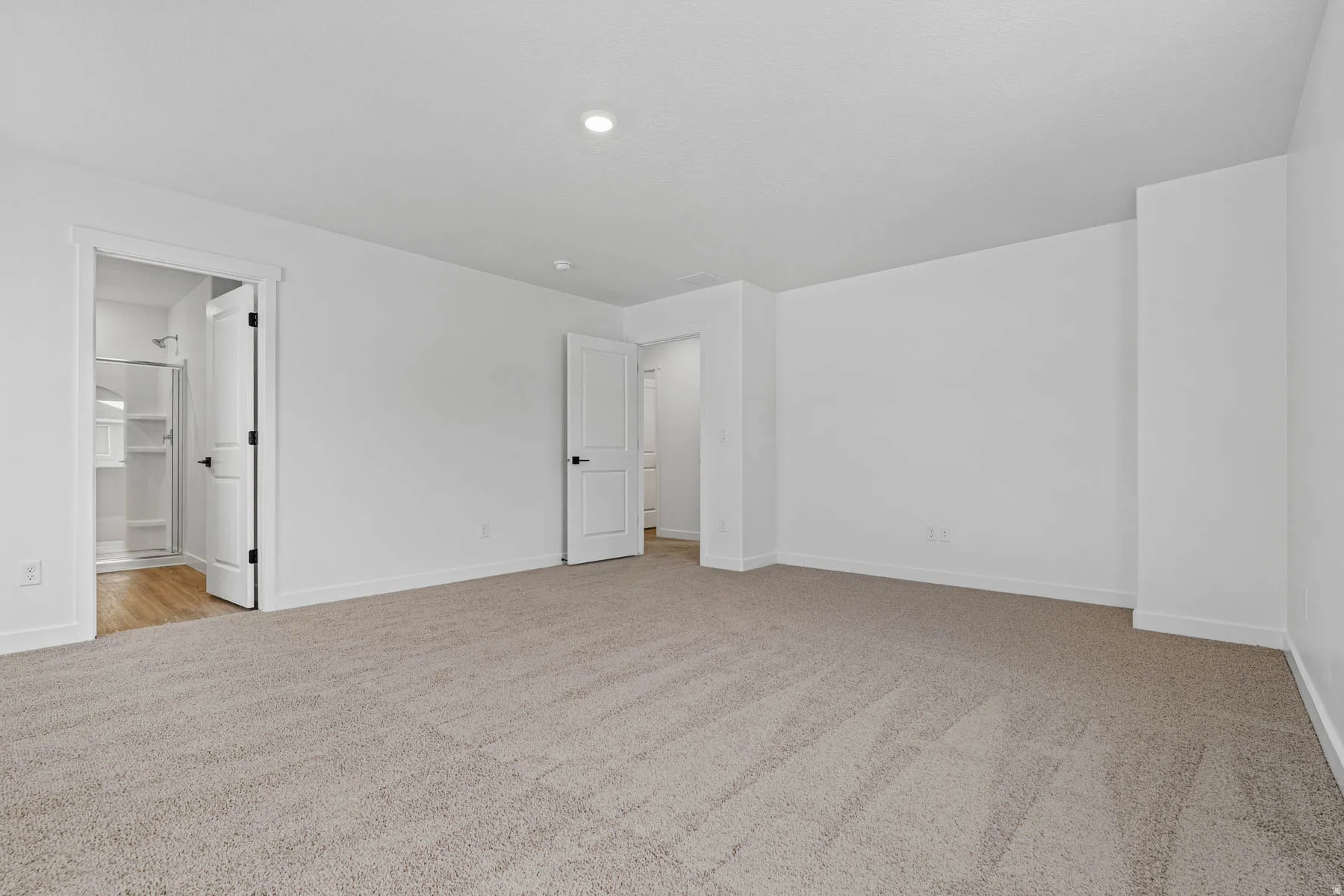 Unfurnished bedroom with light carpet and ensuite bathroom
