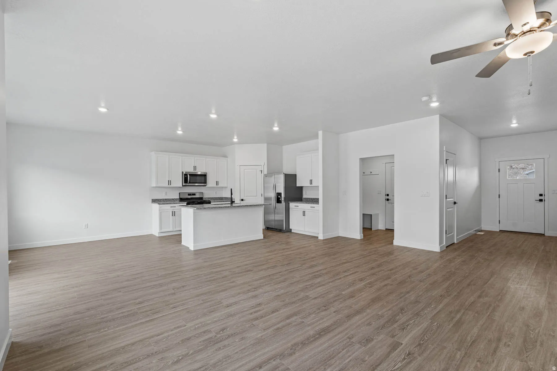 Unfurnished living room featuring a ceiling fan and light wood-style flooring