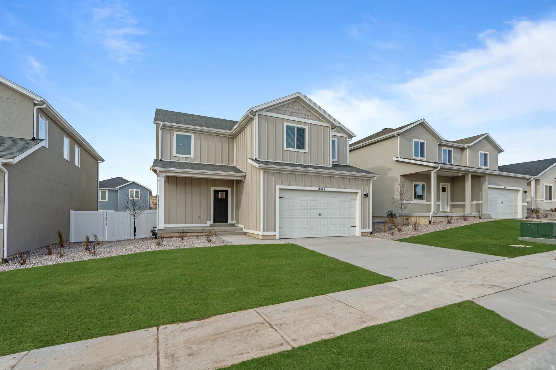 View of front of home with board and batten siding, a garage, driveway, and a gate