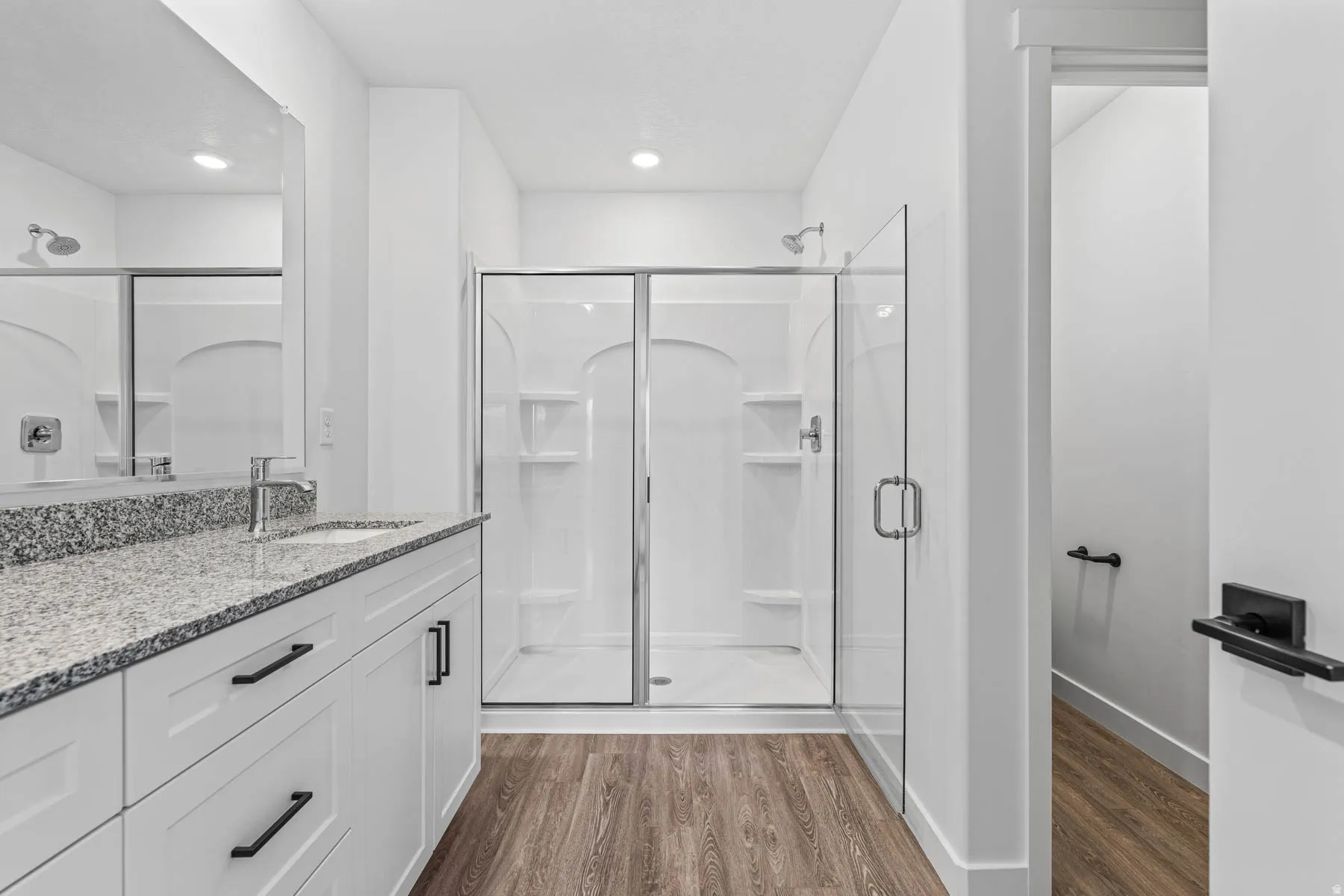 Bathroom with a shower stall, light wood finished floors, and vanity