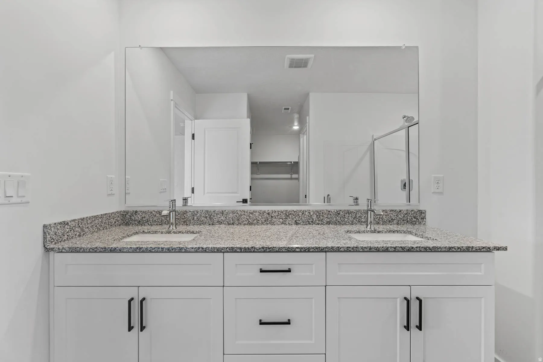 Bathroom with a shower stall, double vanity, and a spacious closet