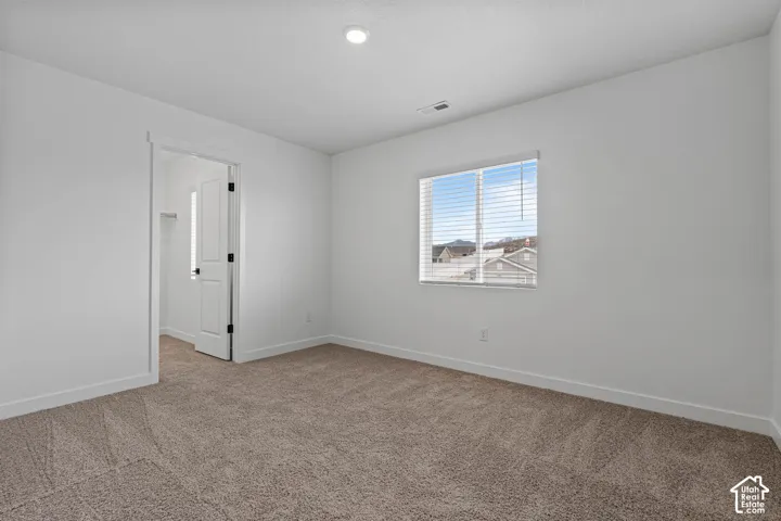 Carpeted spare room featuring baseboards