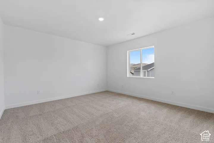 Unfurnished room featuring light carpet and baseboards