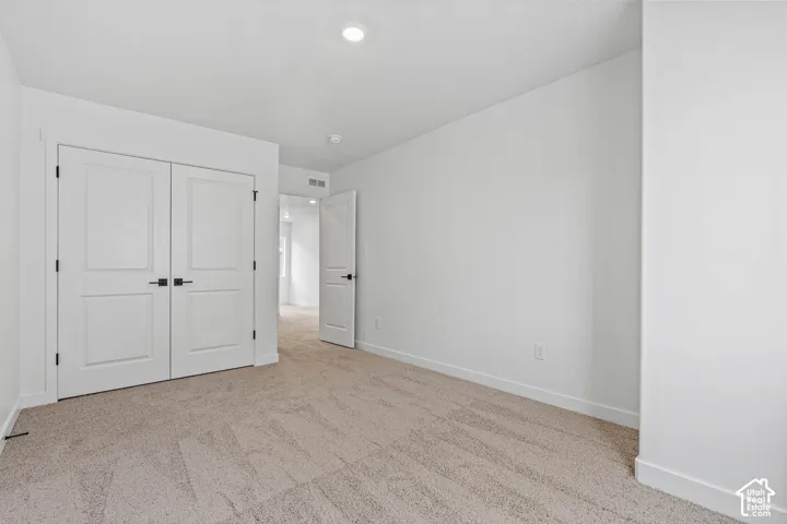 Unfurnished bedroom featuring light colored carpet and a closet