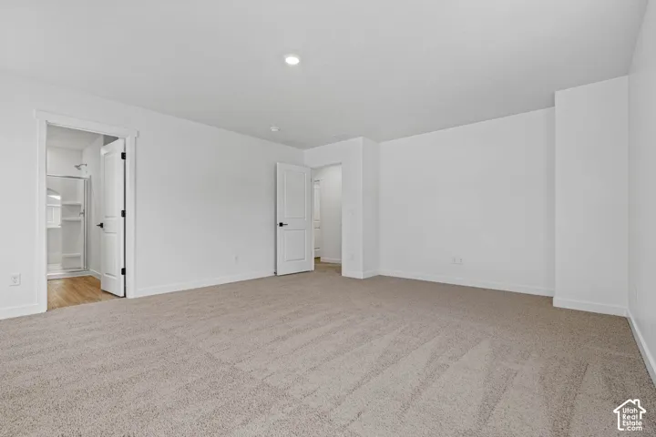 Unfurnished bedroom with light carpet and ensuite bathroom