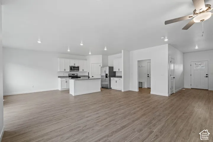 Unfurnished living room featuring a ceiling fan and light wood-style flooring