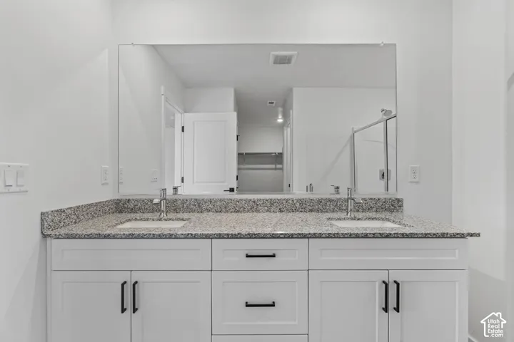 Bathroom with a shower stall, double vanity, and a spacious closet