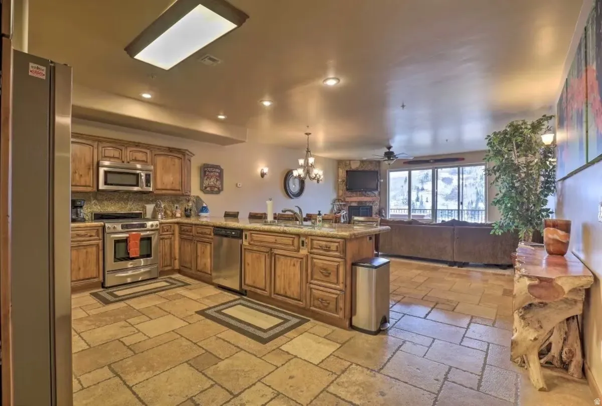 Kitchen peninsula, wood finish cabinetry, open floor plan, and stainless steel appliances