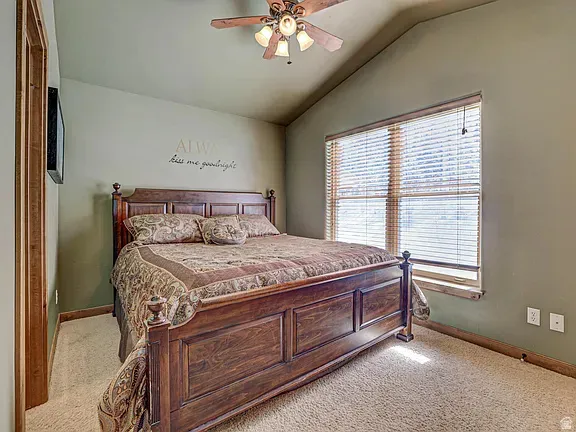 Bedroom featuring lofted ceiling, light colored carpet, and ceiling fan