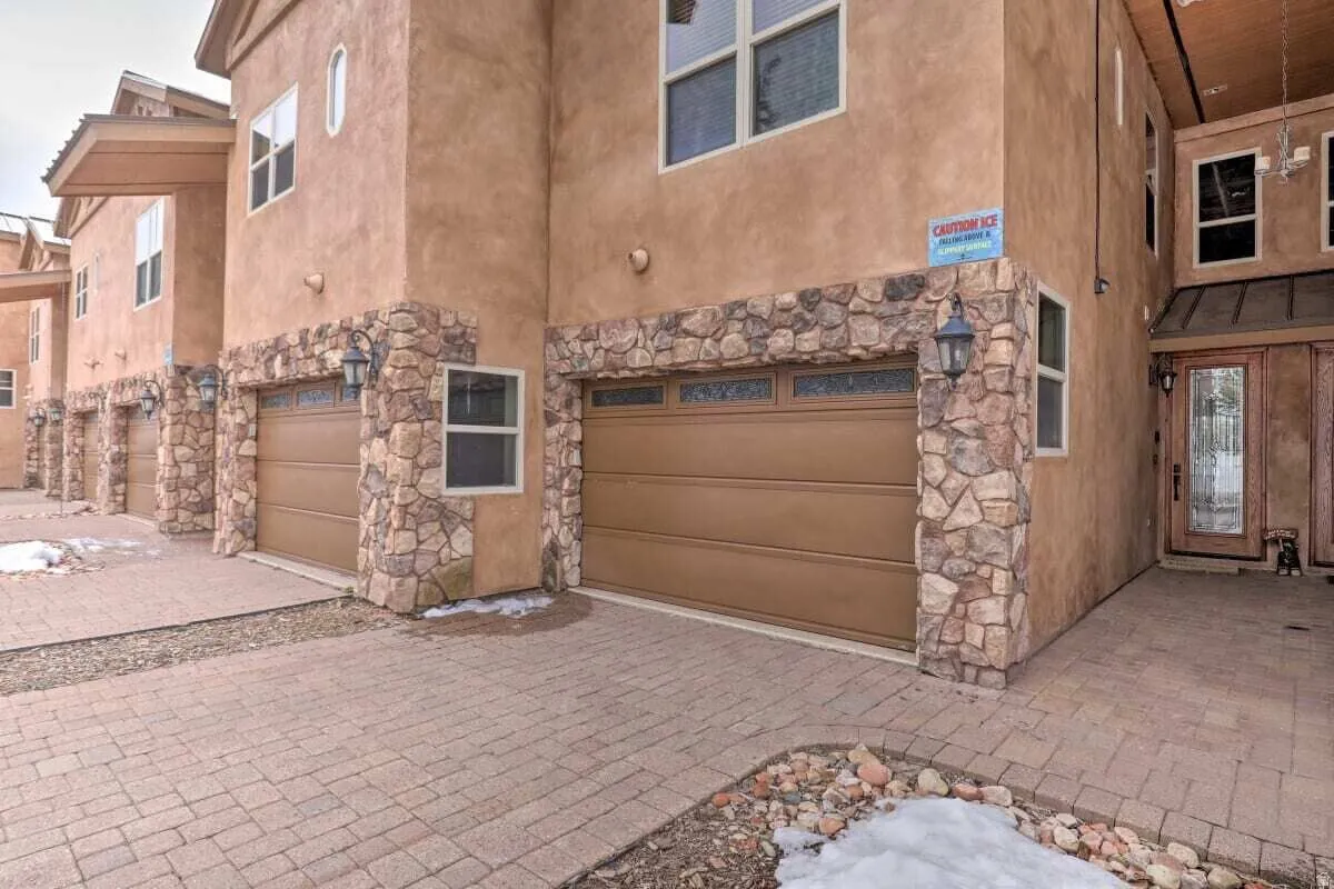 View of front of property with a garage, stone siding, stucco siding, and driveway