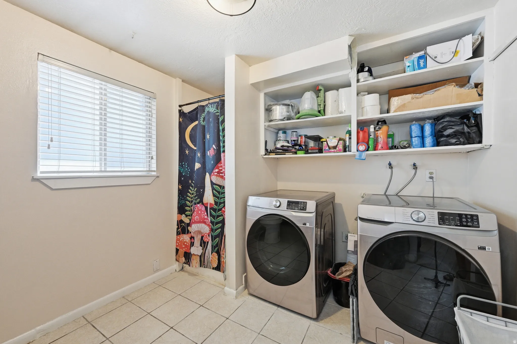 Bathroom /Laundry area featuring independent washer and dryer, light tile patterned floors, and a textured ceiling and shower behind shower curtain