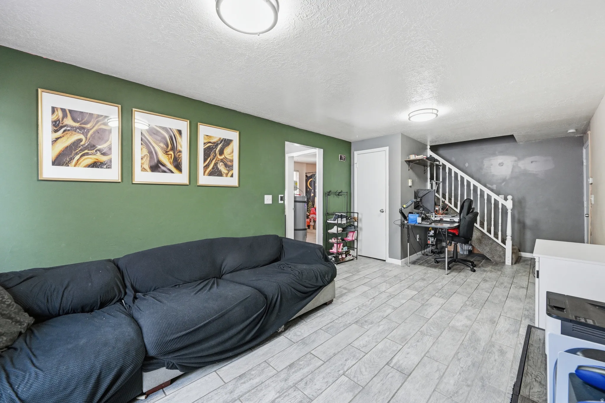 Living room with a textured ceiling, wood tiled floors, and a desk