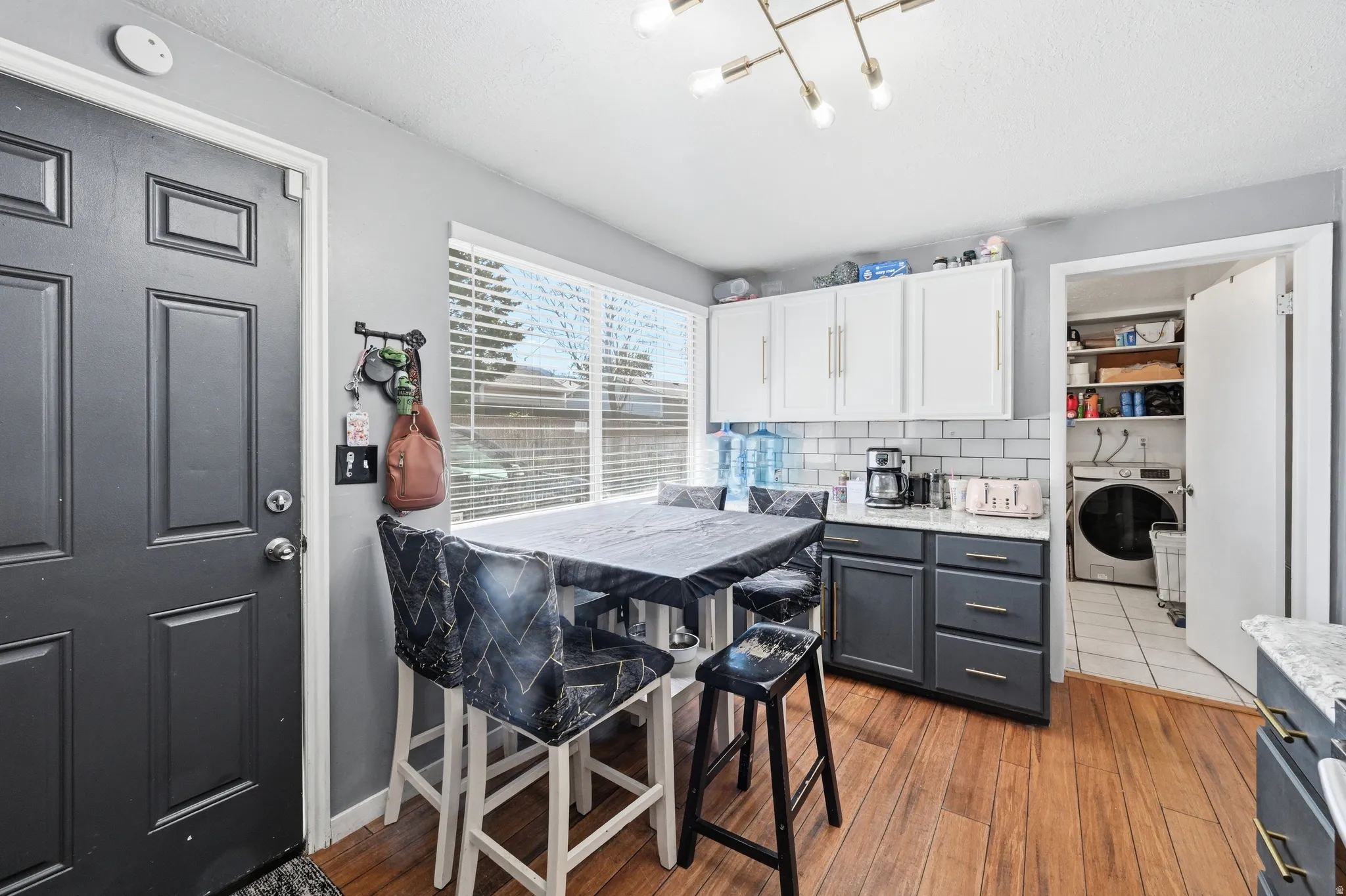 Kitchen featuring two tone cabinetry, light stone countertops, light wood-style floors, and tasteful backsplash