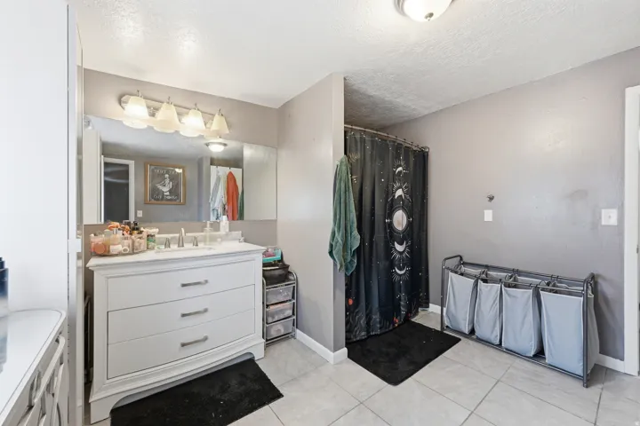 Full bathroom featuring vanity, curtained shower, a textured ceiling, and light tile patterned floors