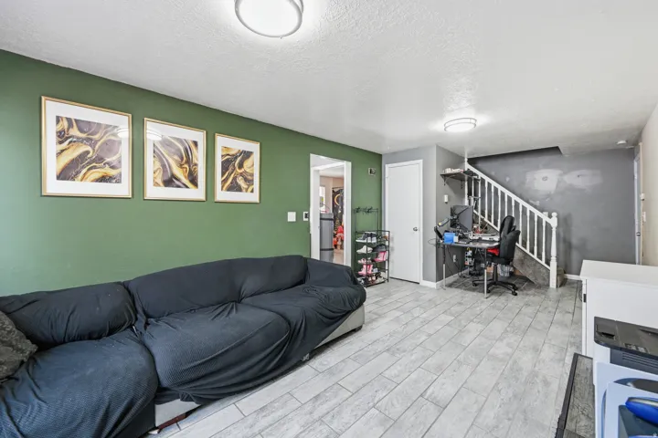 Living room with a textured ceiling, wood tiled floors, and a desk