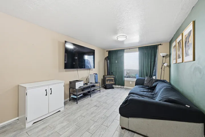 Living room featuring a textured ceiling, wood tiled floors, and a gas stove