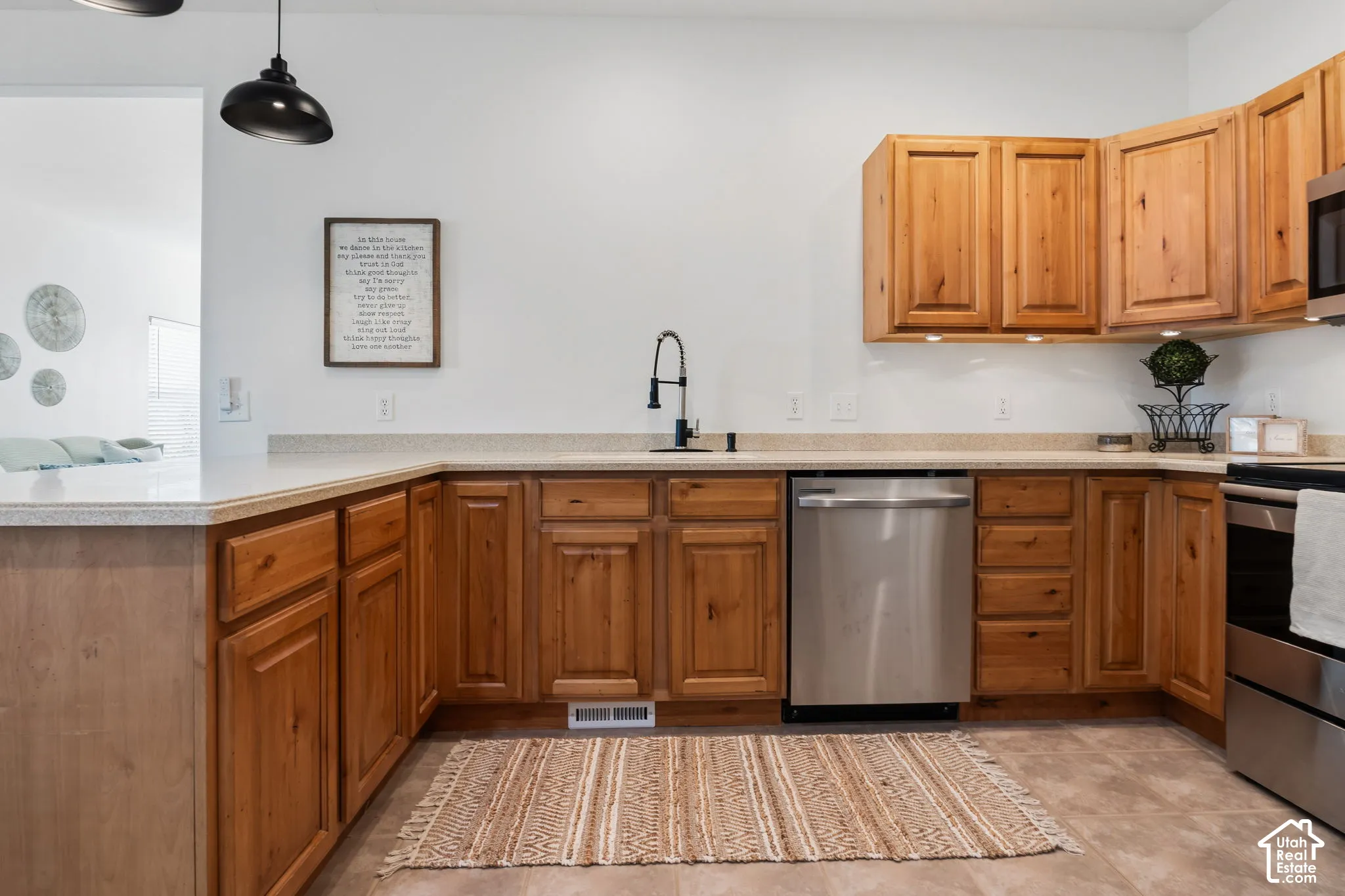 Wood-finish cabinetry, light-toned countertops, stainless steel appliances, and a black gooseneck faucet