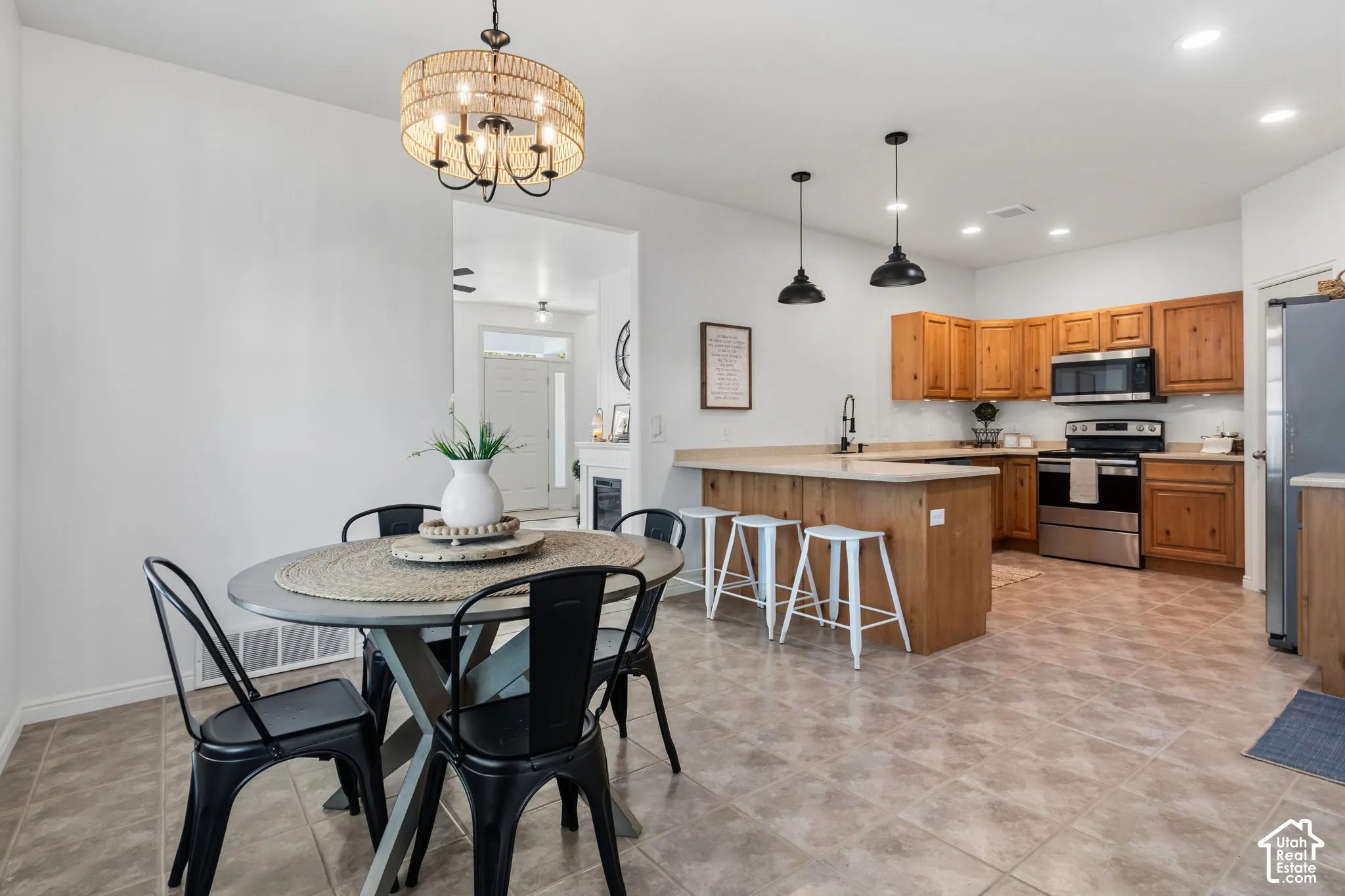 Open-concept kitchen with wood cabinetry, stainless steel appliances, and a breakfast bar
