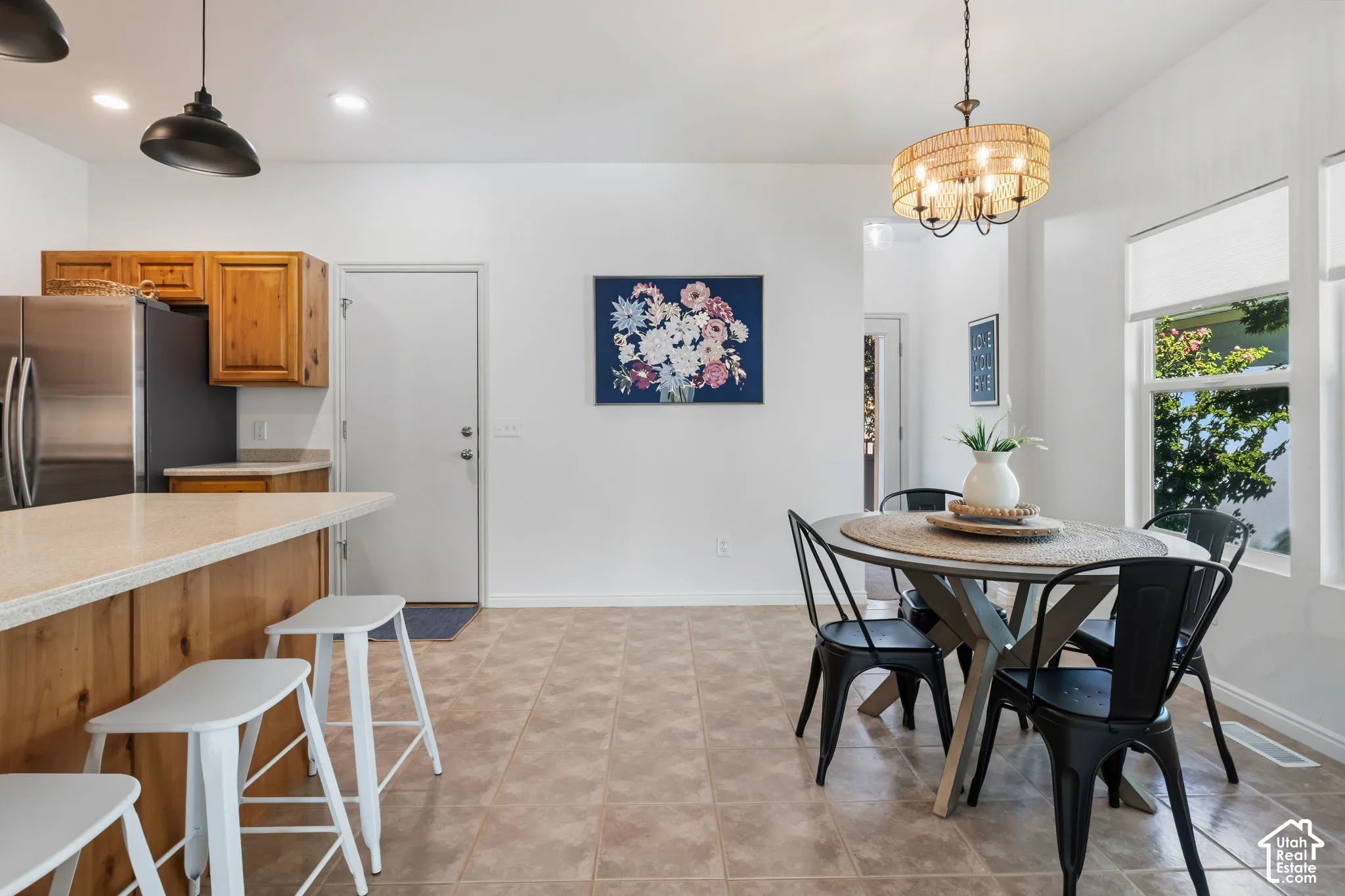 Kitchen and dining area featuring wood cabinetry, stainless steel refrigerator, and a kitchen island with seating