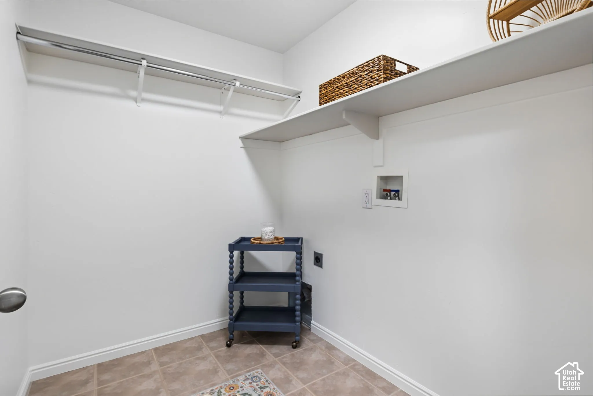 Utility space featuring a tiled floor, built-in shelving, and a clothing rod