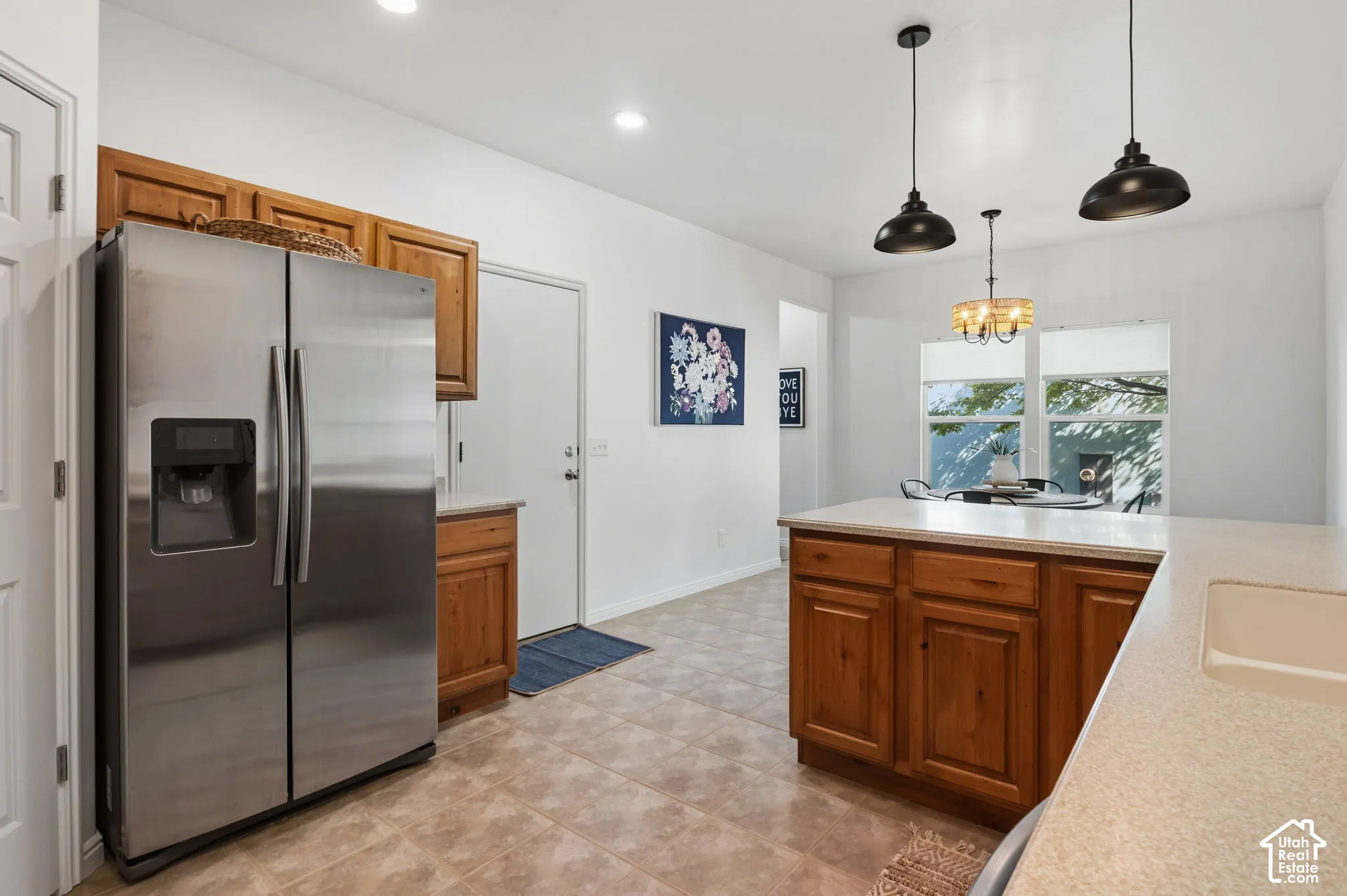 Kitchen featuring tile flooring, wood cabinetry, light-toned countertops, and ceiling-mounted pendant lighting