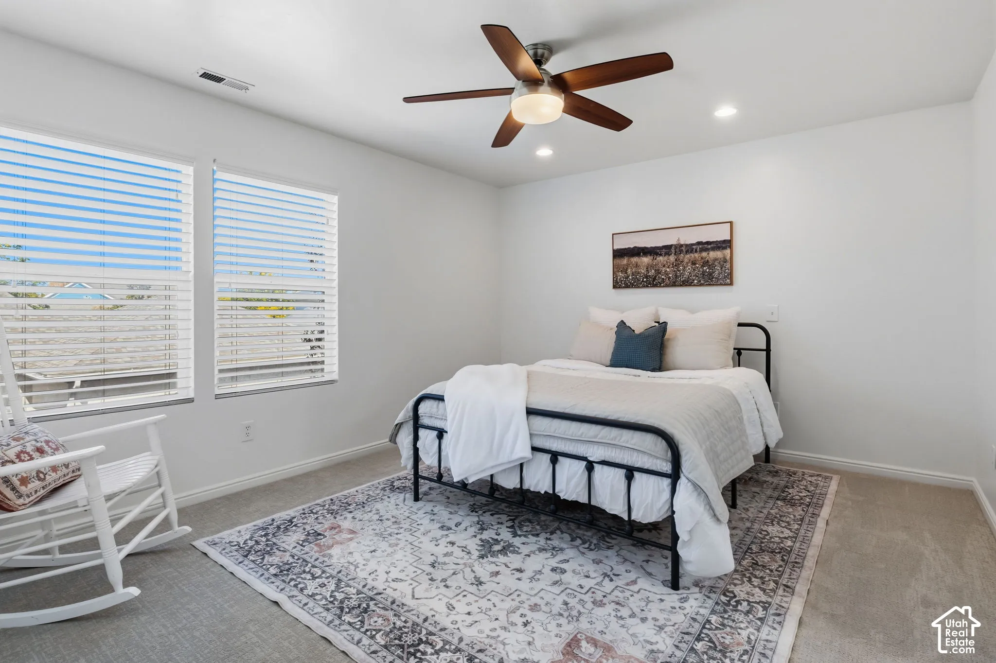 Recessed lighting, ceiling fan with light fixture, two windows with blinds, and neutral carpet flooring