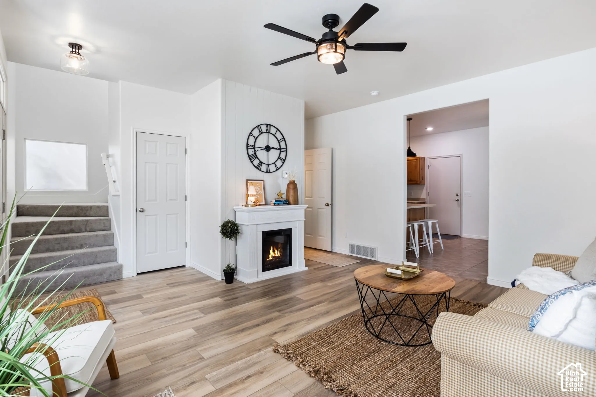 Wood-finish flooring, built-in fireplace, ceiling fan with integrated lighting, recessed lighting, and carpeted staircase