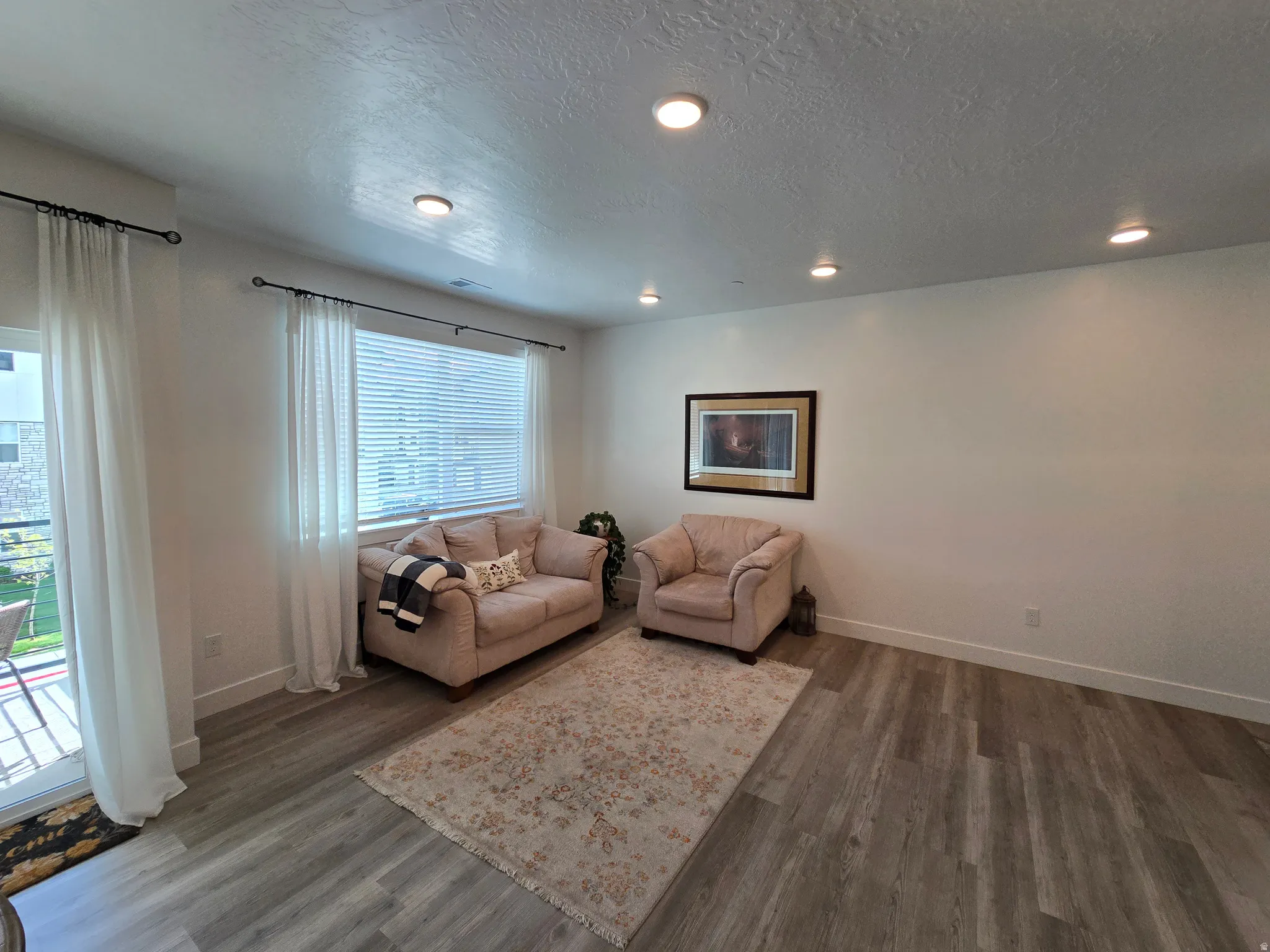 Living area featuring dark wood finished floors, a textured ceiling, and recessed lighting