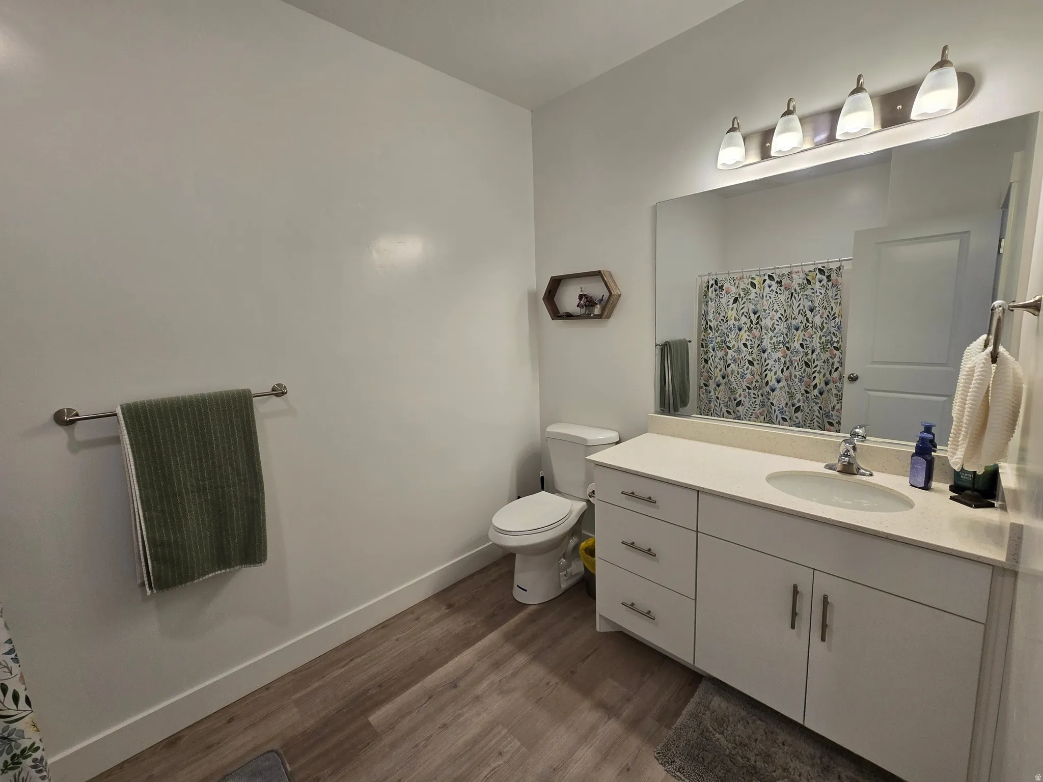 Bathroom with vanity, a shower with curtain, and dark wood-style floors