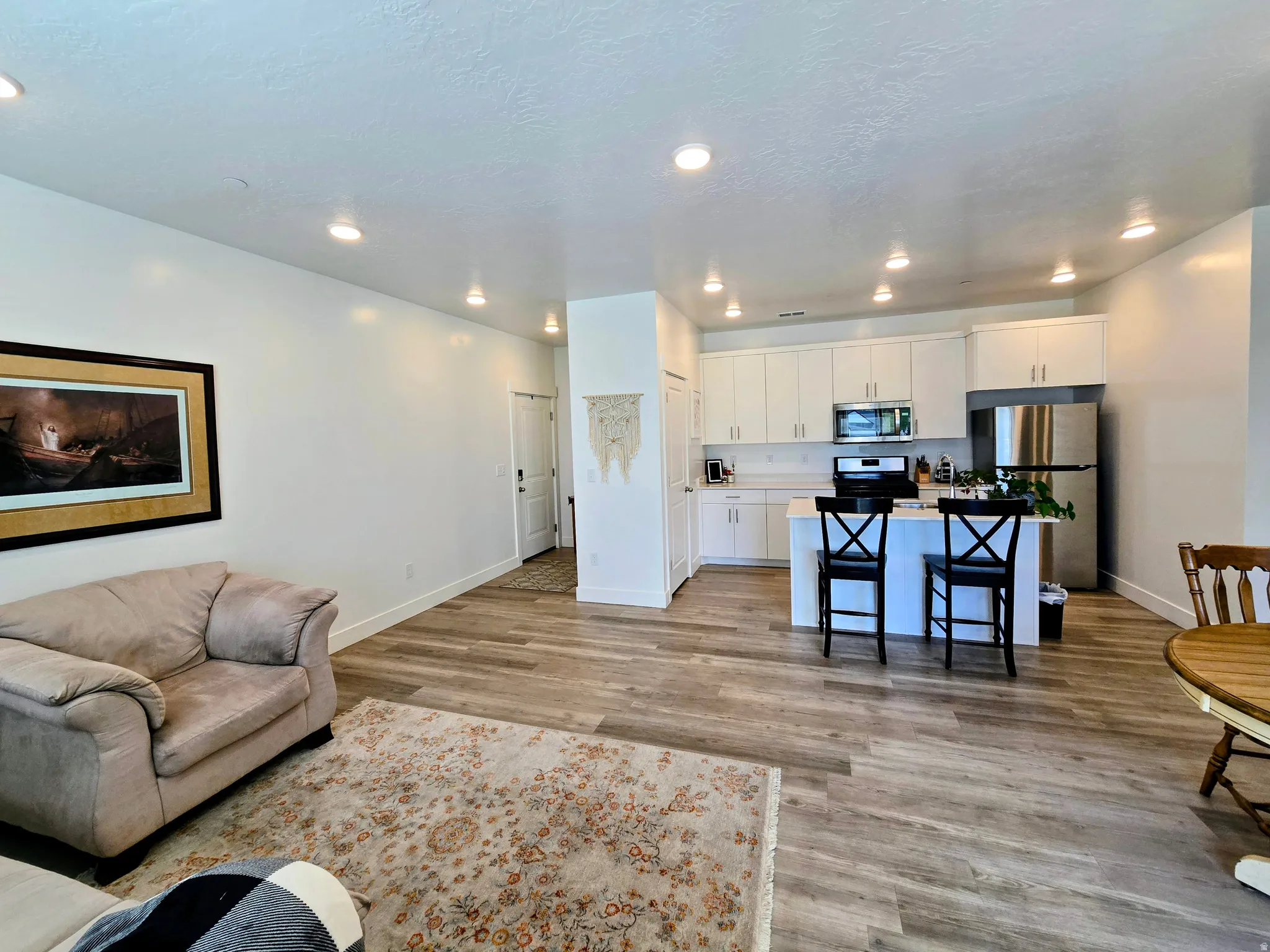 Living area with light wood-type flooring and recessed lighting