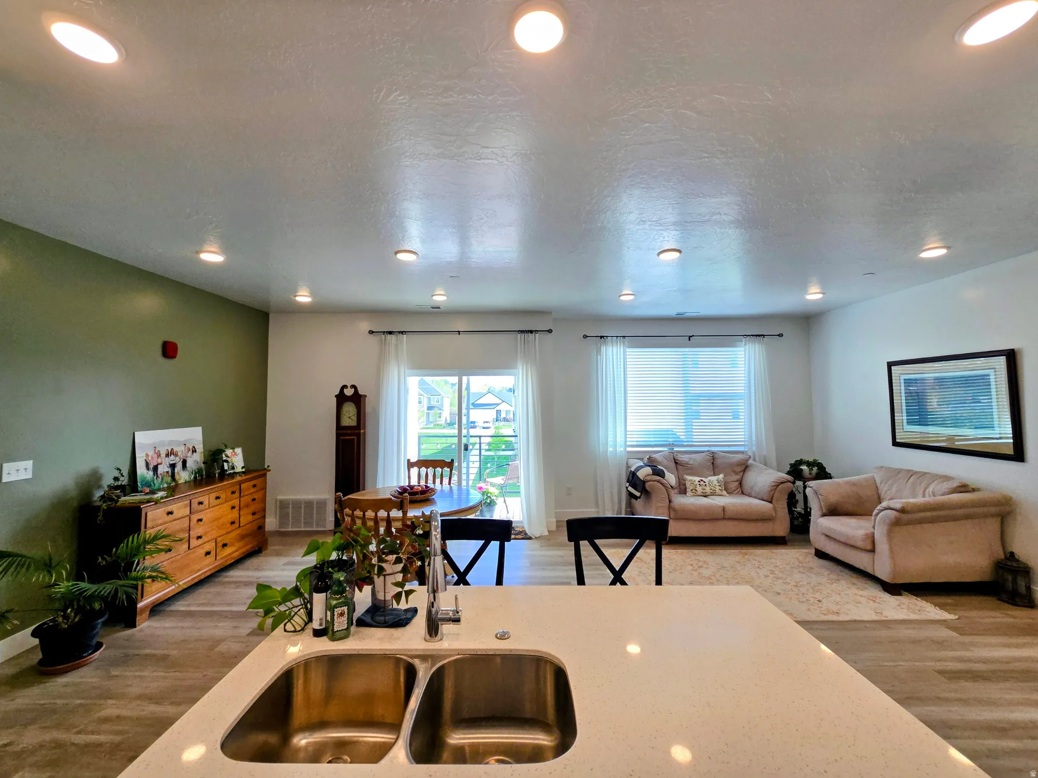 Kitchen featuring light wood finished floors, open floor plan, recessed lighting, a textured ceiling, and light stone counters