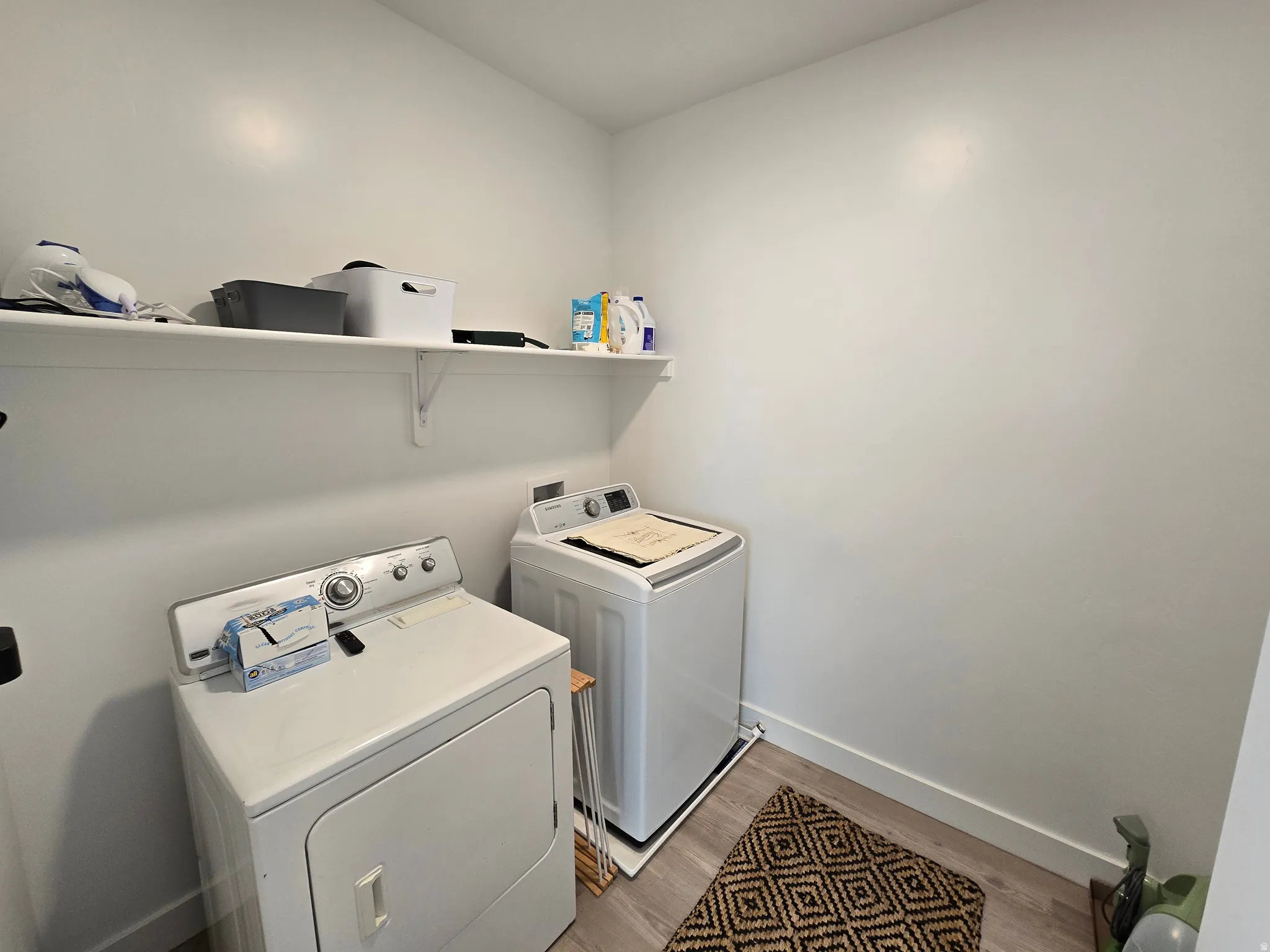 Laundry area with washing machine and dryer and light wood-style flooring