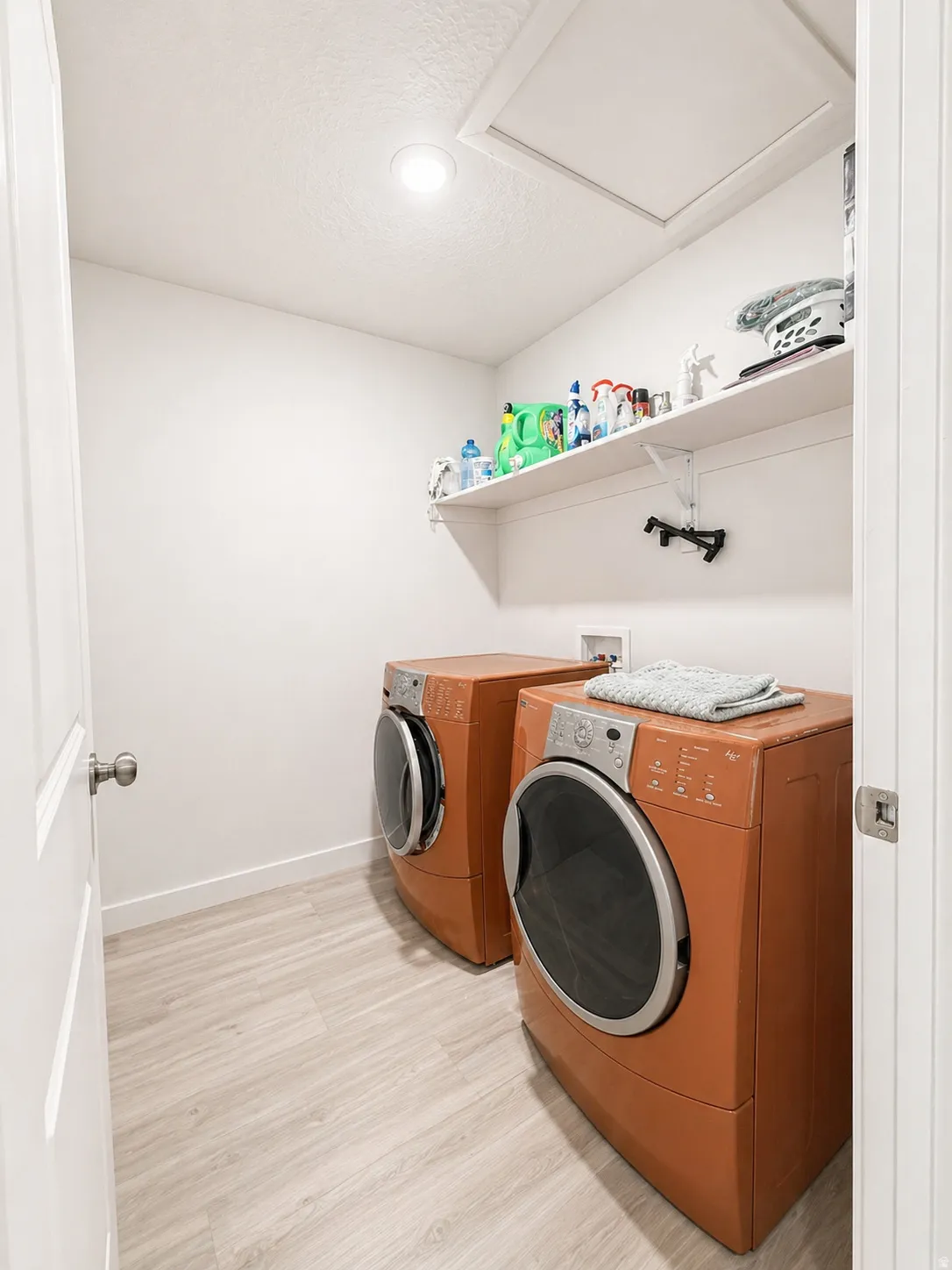 Laundry room featuring light wood-style flooring, washer and clothes dryer, and a textured ceiling