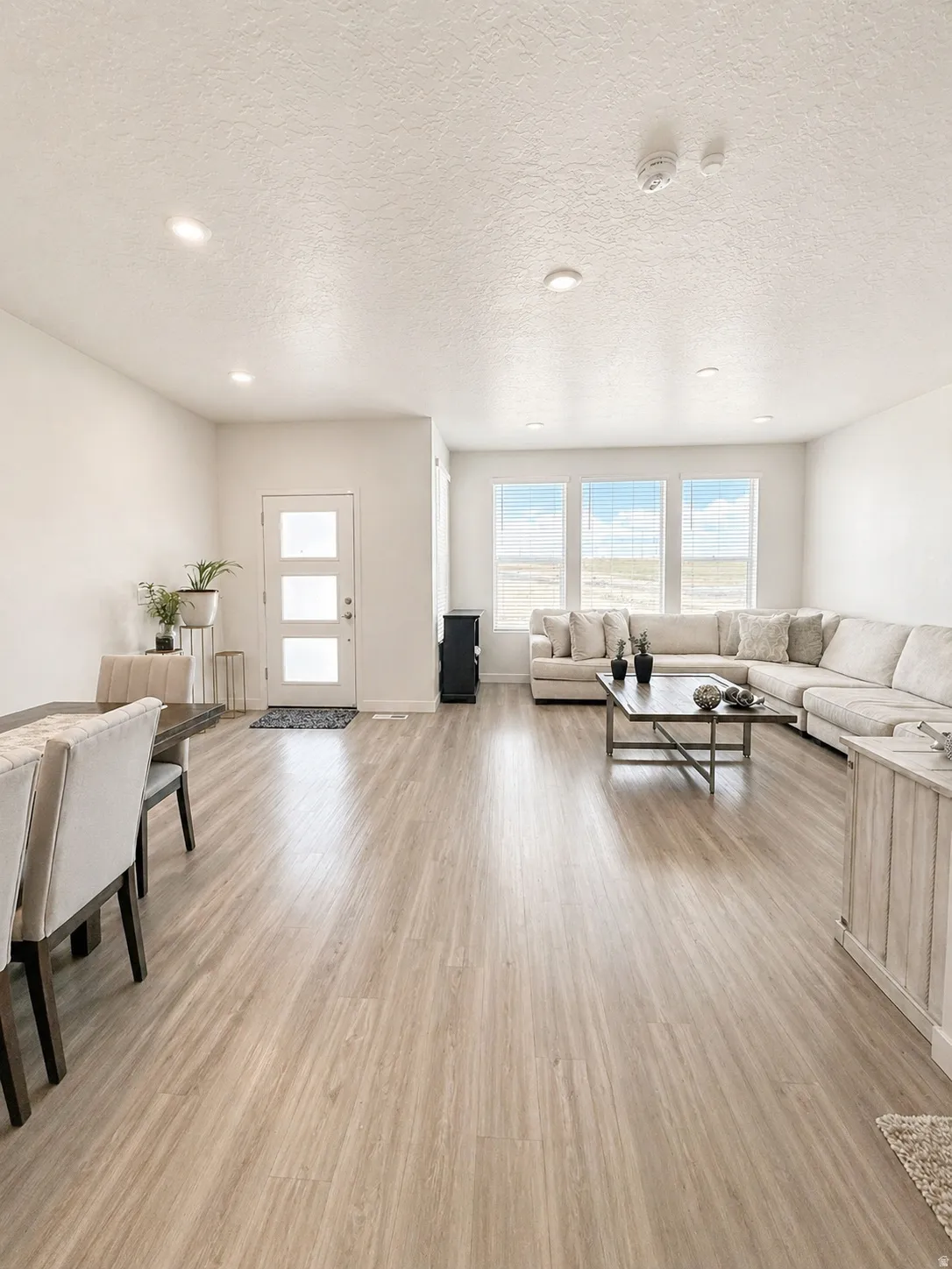 Living room with light wood-style flooring, a textured ceiling, and recessed lighting