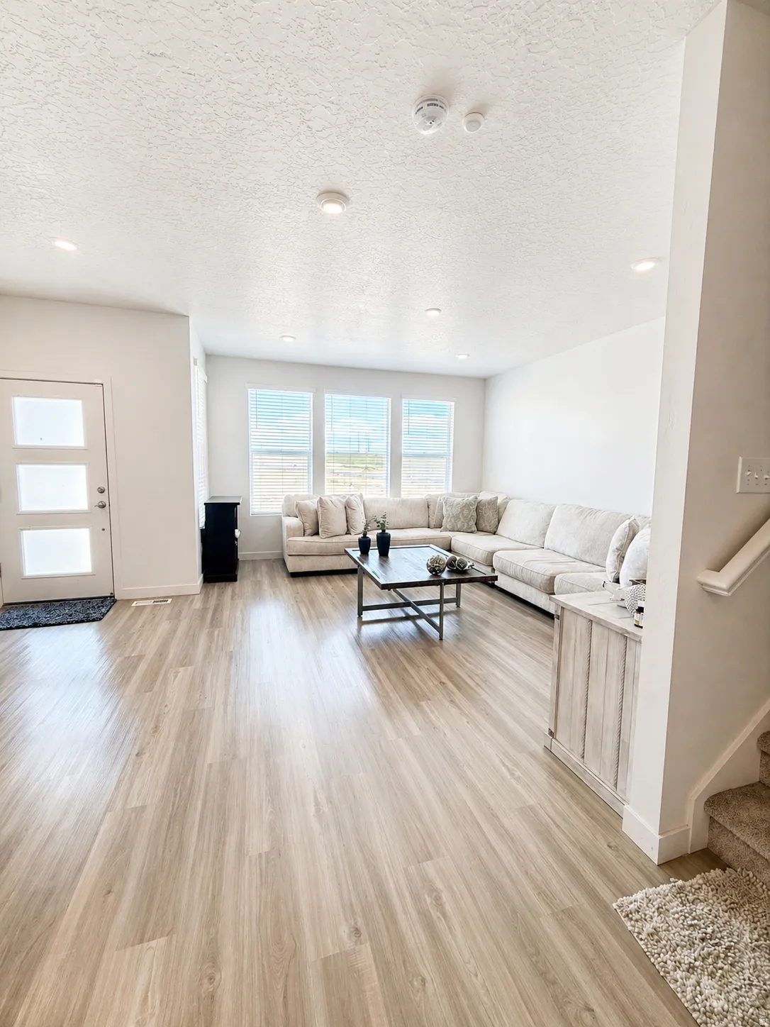 Living area with light wood-style flooring, a textured ceiling, and recessed lighting